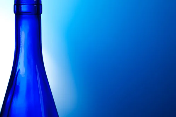 Блакитна пляшка вина на синьому фоні — стокове фото