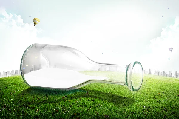 Glass bottle with milk on green grass — Stock Photo, Image