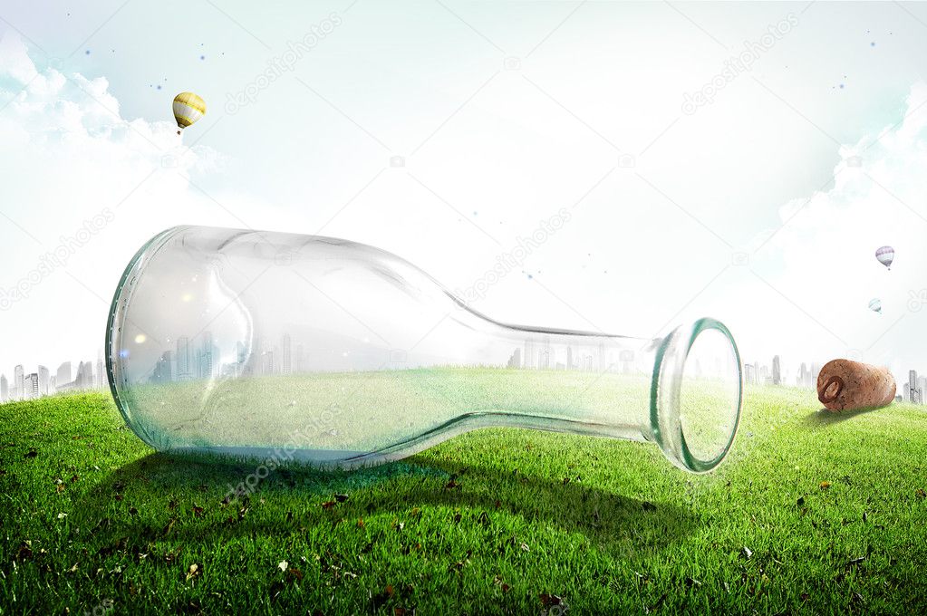 Empty glass bottle on green grass