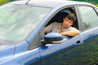 Smiling young man in the car clipart