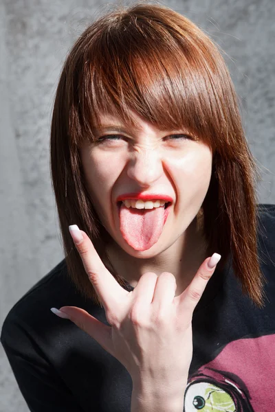 Close up portrait of cool young girl showing her tongue and rock — Stock Photo, Image