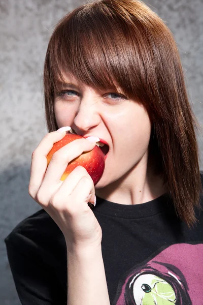 Junges schönes Mädchen beißt in einen roten Apfel. — Stockfoto