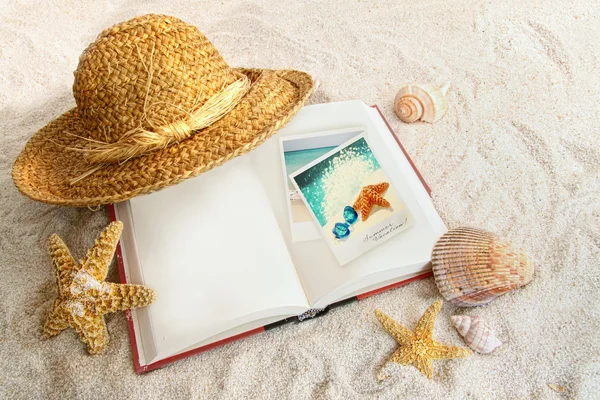 Книга с соломенной шляпой и морскими песками — стоковое фото