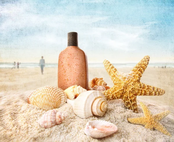Opalovací krém a mušle na pláži — Stock fotografie