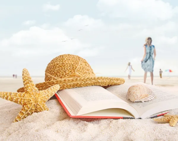 Chapéu de palha, livro e conchas na areia — Fotografia de Stock