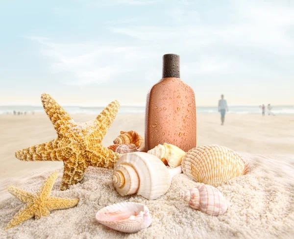 Suntan lotion and seashells on the beach — Stock Photo, Image