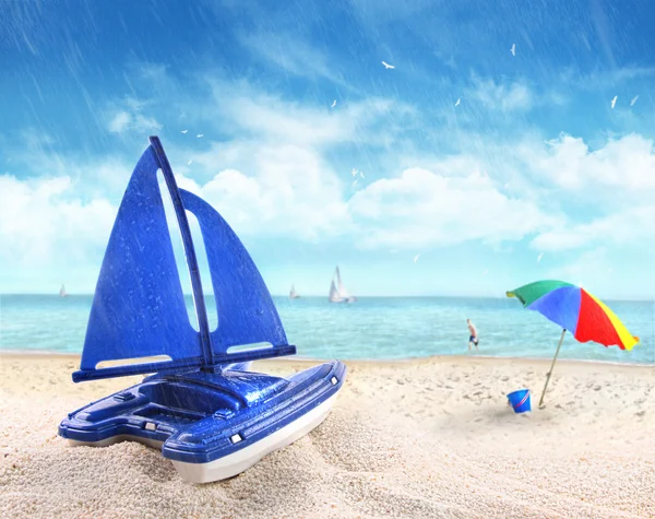 Spielzeug-Segelboot im Sand mit Strand-Szene — Stockfoto