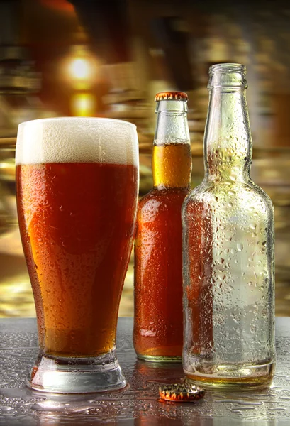 Стакан пива с бутылками — стоковое фото