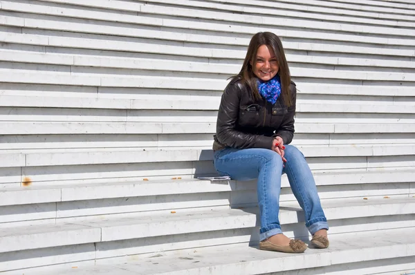 Kobieta siedzi na marmurowych schodach i uśmiechy — Zdjęcie stockowe