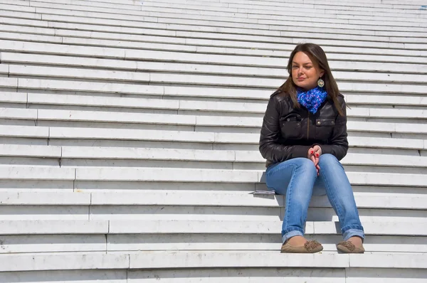 stock image Woman sitting on the marble steps squinting in the sunlight