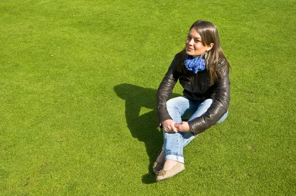 Dziewczyna siedzi na zielony trawnik — Zdjęcie stockowe