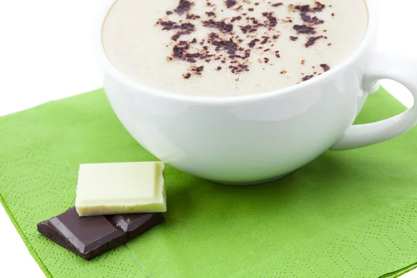 Чашка капучино и шоколад на салфетке — стоковое фото