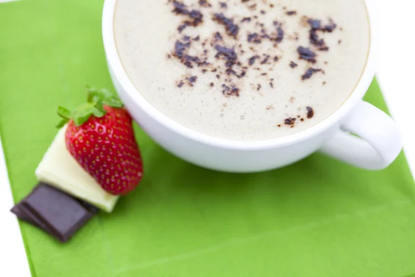 En cappuccino med sjokolade og jordbær på en serviett. – stockfoto