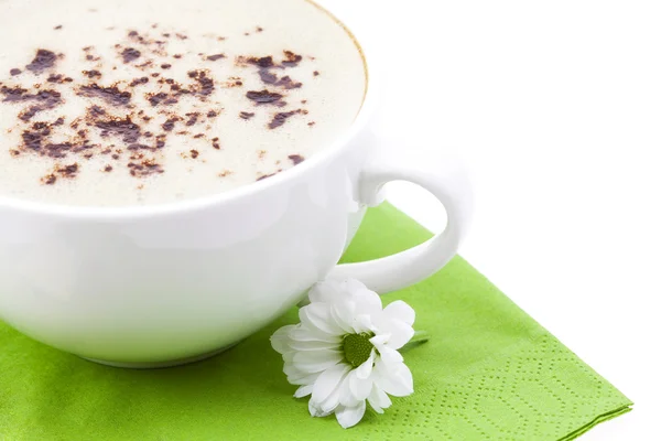 Une tasse de cappuccino et une fleur sur une serviette — Photo