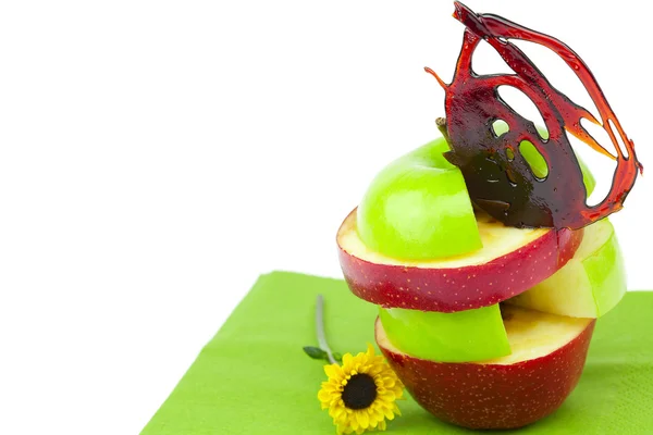 Нарезанные яблоки с карамелью и цветок на салфетке — стоковое фото