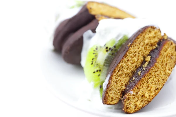 Torta con panna e kiwi su un piatto isolato su bianco — Foto Stock