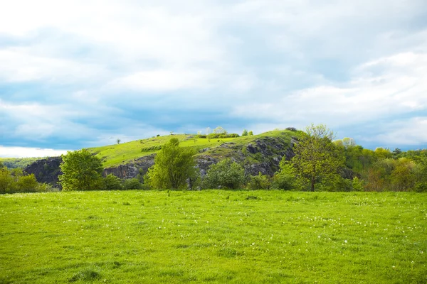 Холм на фоне зеленого поля — стоковое фото