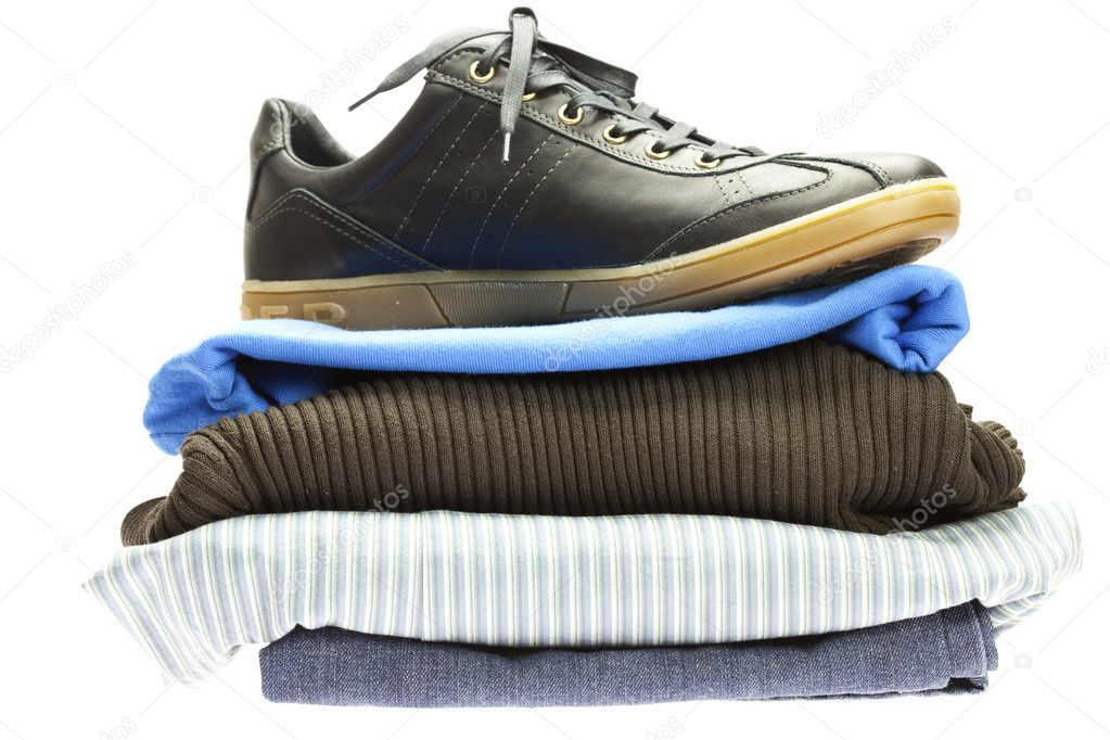 Sports shoes lying on the mountain of clothes isolated on white