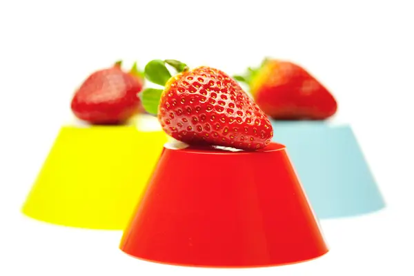 Aardbeien en gekleurde kommen geïsoleerd op wit — Stockfoto
