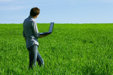 Young man using a laptop outdoors clipart