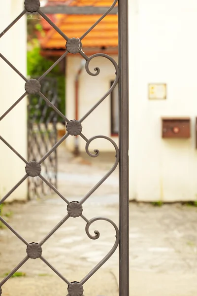 Внешний вид дома через кованый забор — стоковое фото