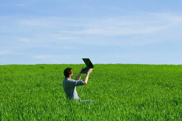 Hombre joven usando un ordenador portátil al aire libre — Foto de Stock