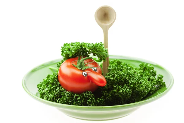 Tomate mit Nase auf einem grünen Teller liegend mit einem Löffel isoliert — Stockfoto