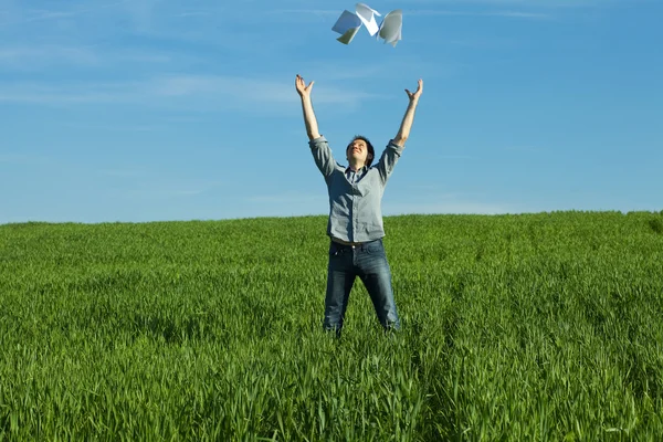 若い男が、緑の野原で、紙を投げ — ストック写真