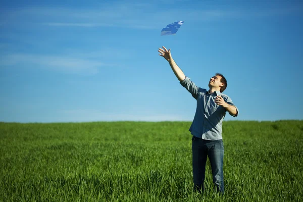 Молодой человек бросил бумагу в зеленое поле — стоковое фото