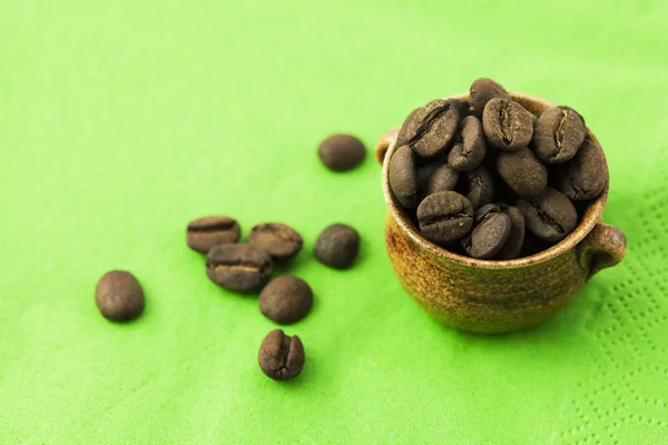 Small jar with coffee beans on green background — Stock Photo, Image