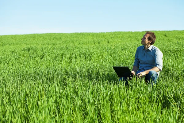 Młody człowiek korzysta z laptopa w polu — Zdjęcie stockowe