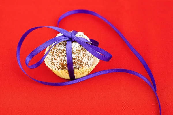 Торт увенчанный кокосовой лентой на красном фоне — стоковое фото