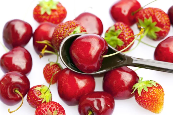 Cherry en aardbei in een lepel geïsoleerd op wit — Stockfoto