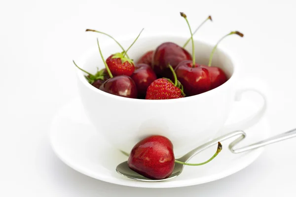 Taza platillo cuchara cerezas y fresas aisladas en blanco — Foto de Stock