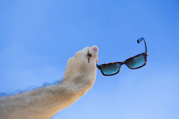Óculos nas mãos contra o céu — Fotografia de Stock