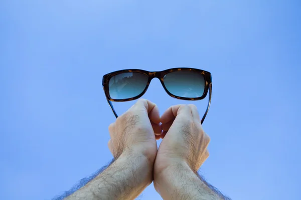 Glasses in the hands against the sky — Stock Photo, Image