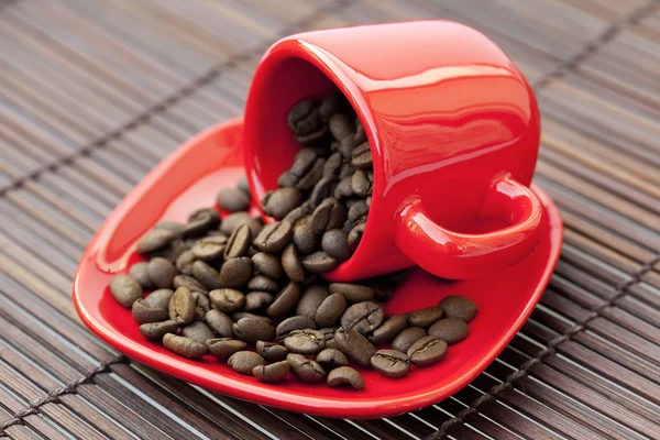 Kop en schotel en koffie bonen op een bamboe-mat — Stockfoto