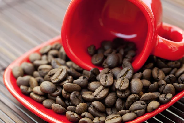 カップとソーサーと竹のマットの上のコーヒー豆 — ストック写真