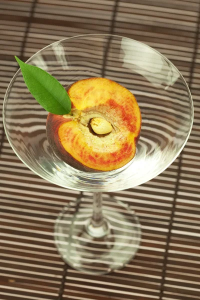 Pêssego no vidro martini em uma esteira de bambu — Fotografia de Stock