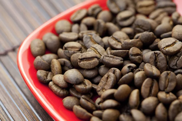 Soucoupe et grains de café sur un tapis de bambou — Photo