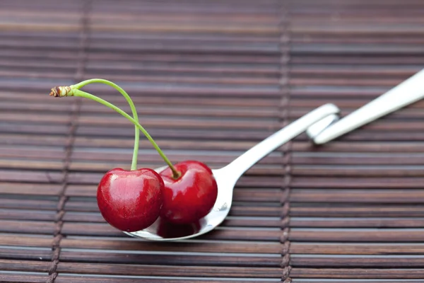 Cherry v lžíci na bambusové rohoži — Stock fotografie