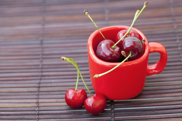 Cherry en cup op bamboe mat — Stockfoto