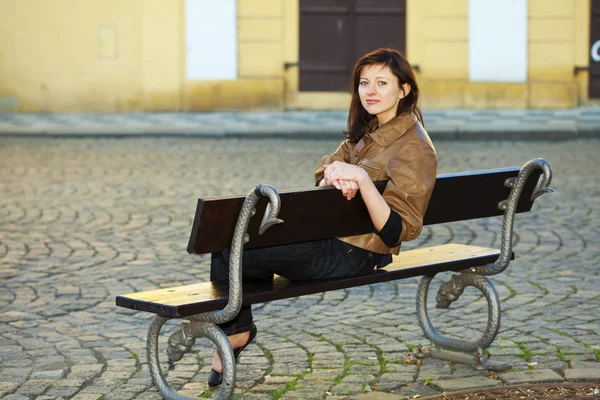 Beautiful young woman sitting on a bench — Stock Photo, Image