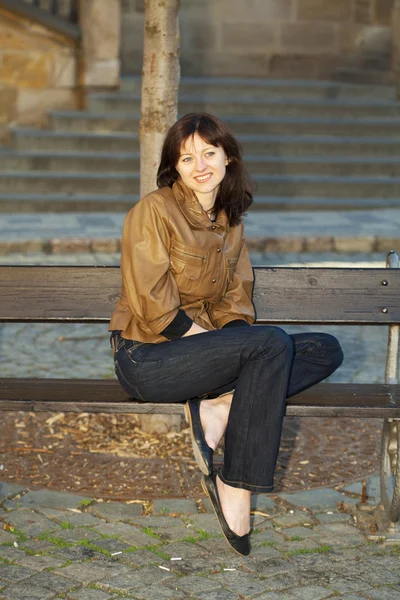 Vacker ung kvinna sitter på en bänk — Stockfoto