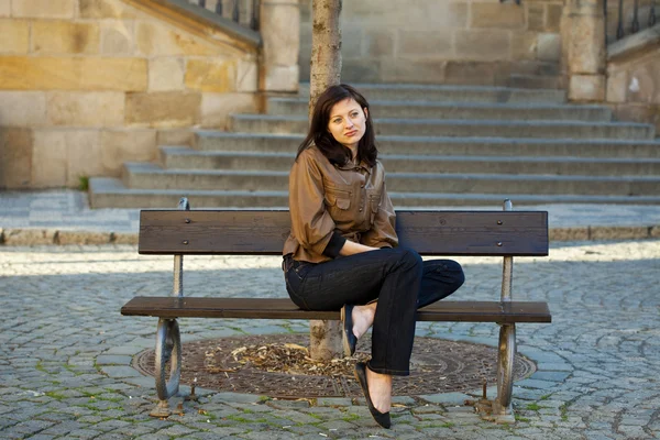 Bela jovem mulher sentada em um banco — Fotografia de Stock