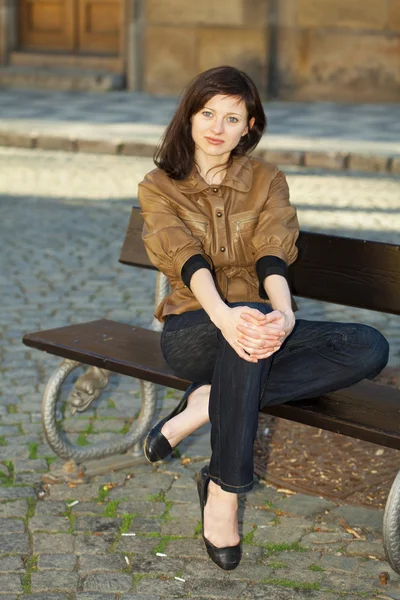 Güzel genç bir kadın bankta oturuyor. — Stok fotoğraf
