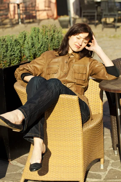 Bela jovem mulher sentada em uma cadeira de vime — Fotografia de Stock