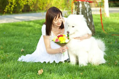 Gelin ile köpek samoyed çimlerde oturuyor.