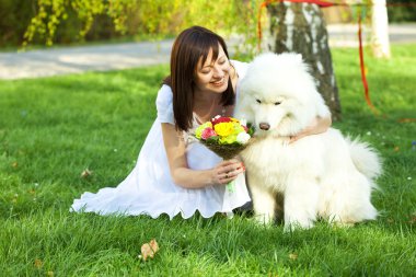 Gelin ile köpek samoyed çimlerde oturuyor.