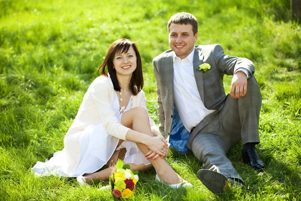 Just married in a flowering garden sitting on the grass — Stock Photo, Image